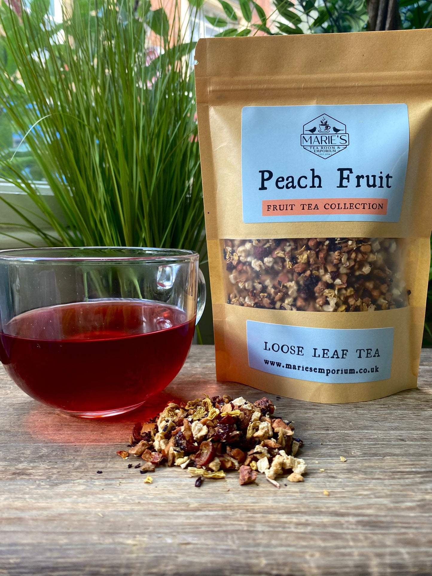 Marie's Peach Fruit loose leaf tea package with a glass of tea on a wooden surface