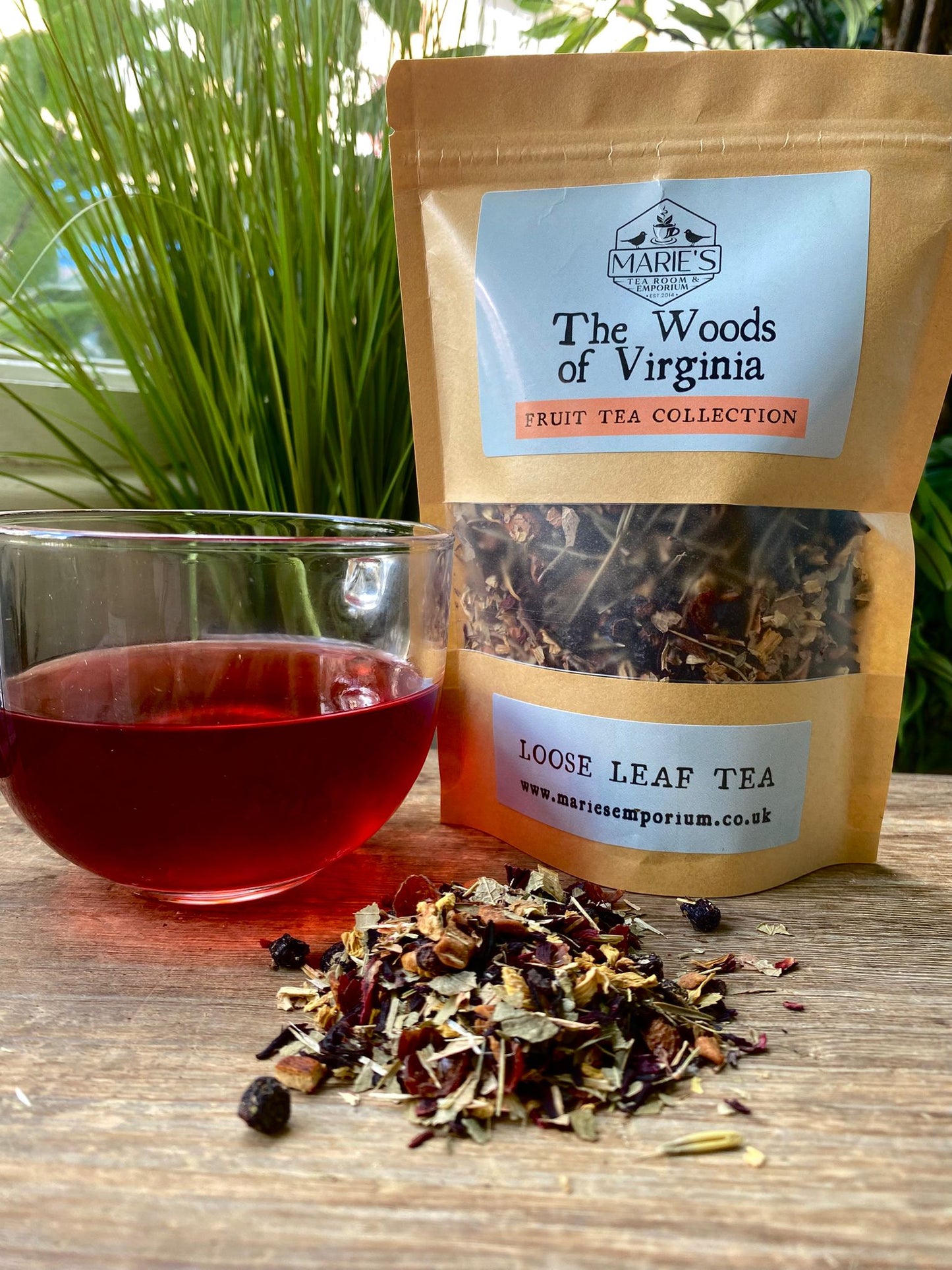 maries Loose leaf tea from 'The Woods of Virginia' with a glass of brewed tea on a wooden surface.