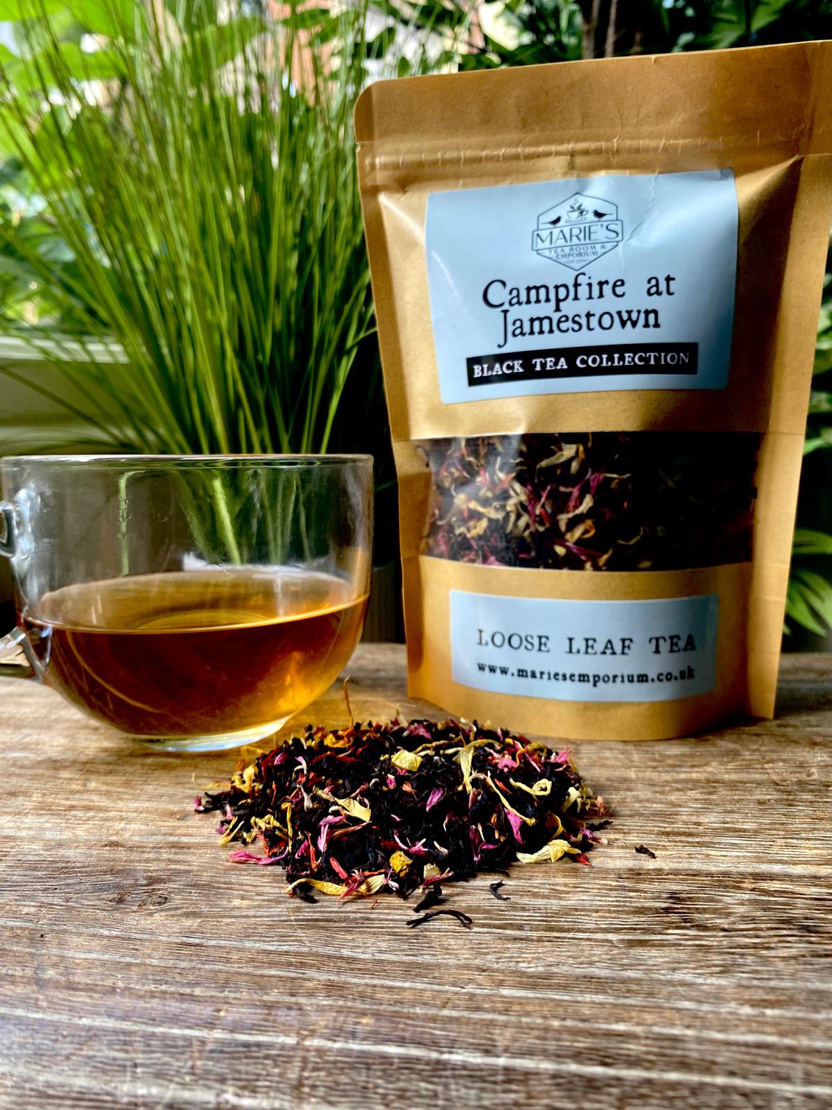 Campfire at Jamestown loose leaf tea package with a glass of tea on a wooden surface