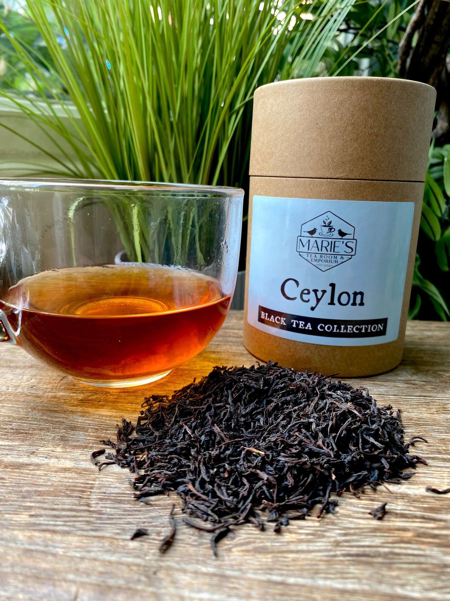 Ceylon black tea collection with a jar and a cup of tea on a wooden surface.
