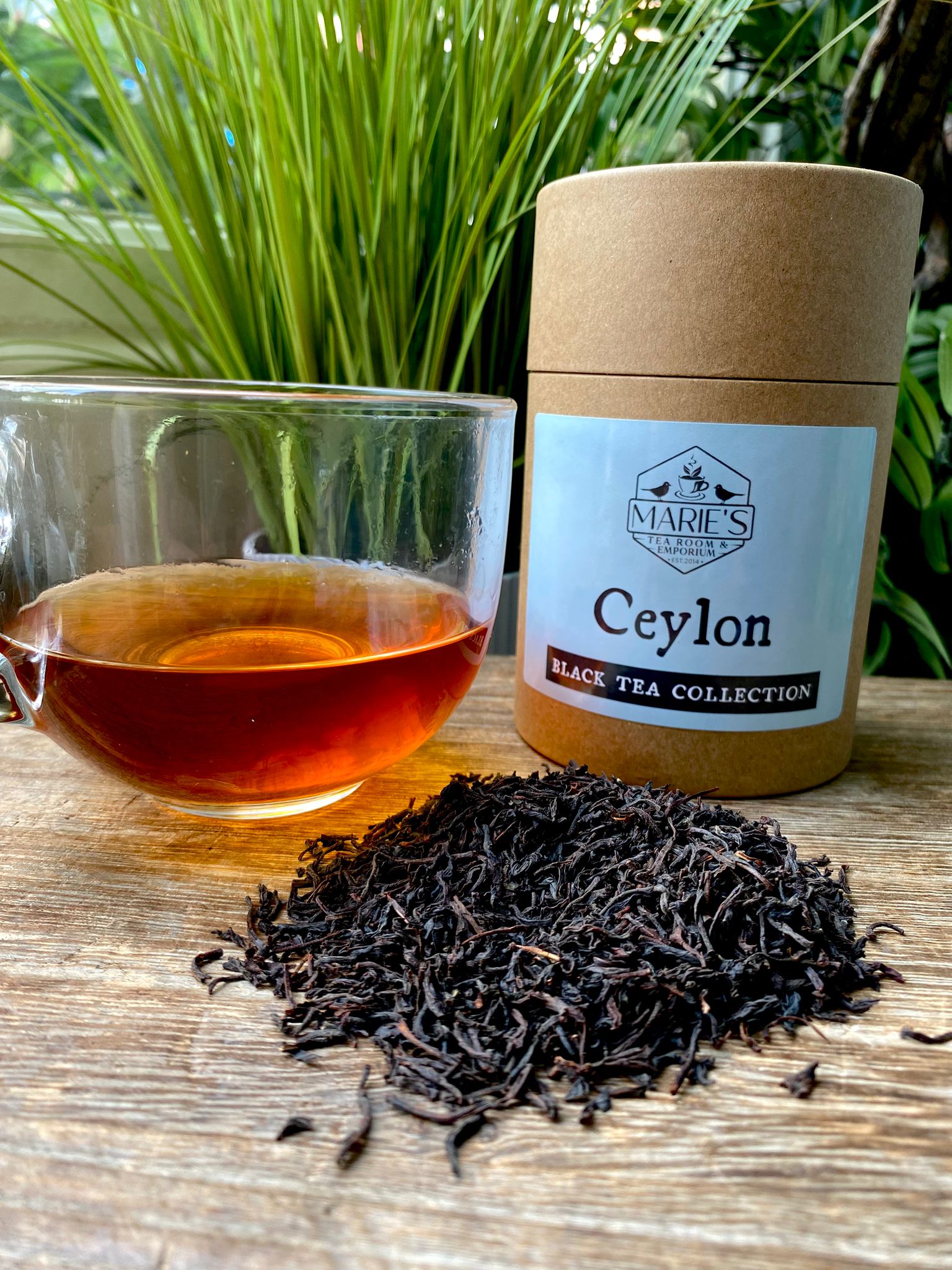Ceylon black tea collection with a jar and a cup of tea on a wooden surface.