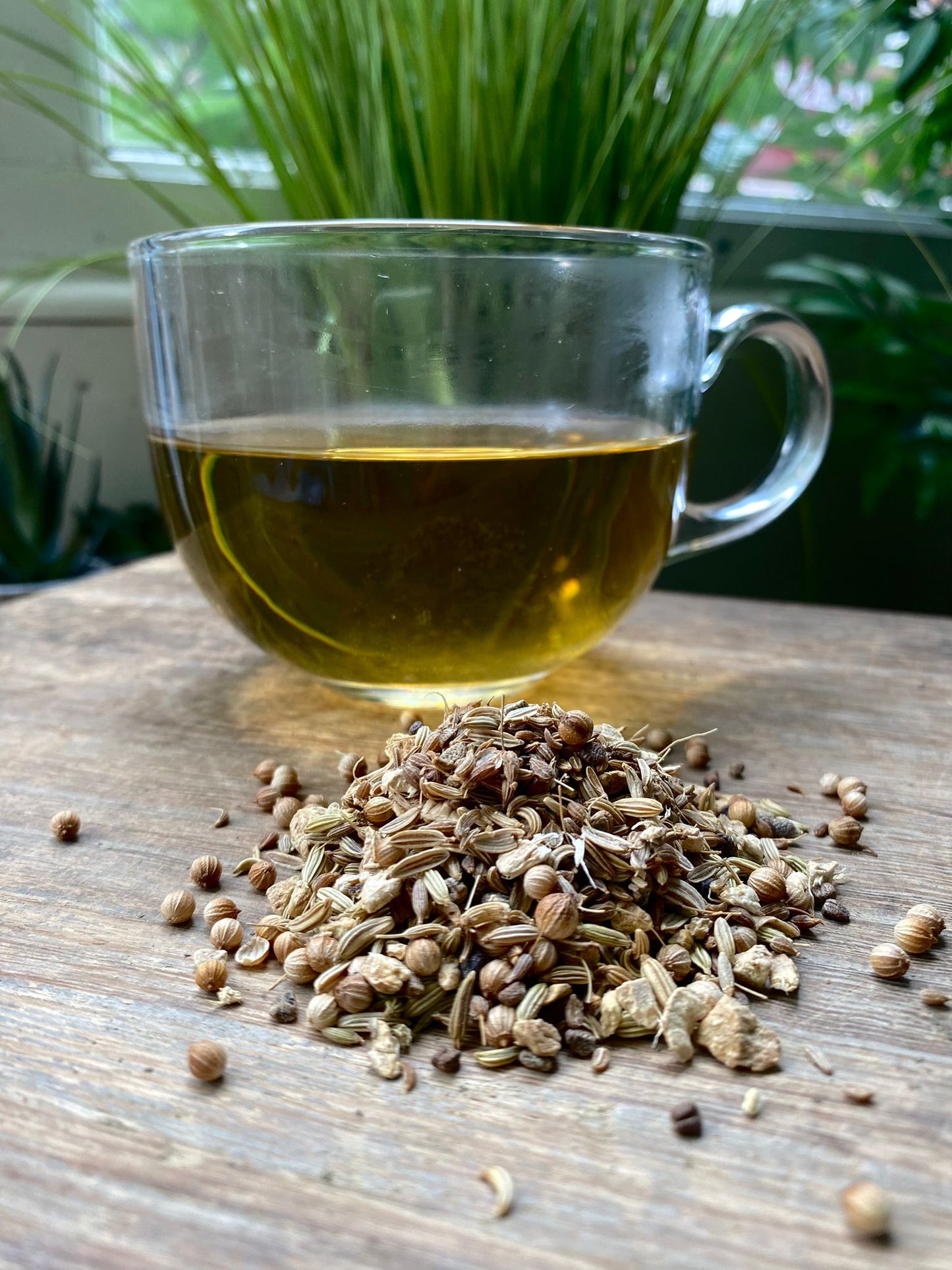 Marie’s Detox loose leaf tea with brewed herbal tea in a clear glass mug and loose tea leaves on a wooden surface