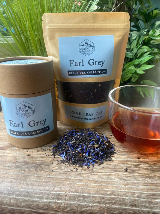 Earl Grey black tea collection with packaging, loose leaves, and brewed tea on a wooden surface.