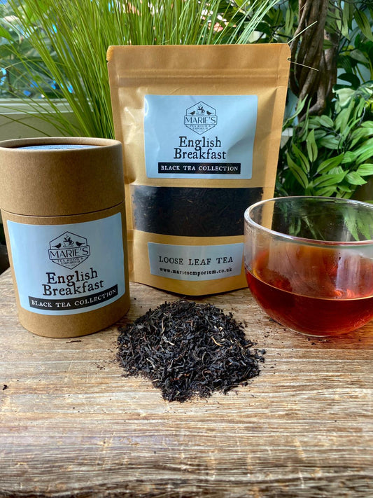Maries English Breakfast black tea collection with packaging, loose leaves, and a cup of tea on a wooden surface.