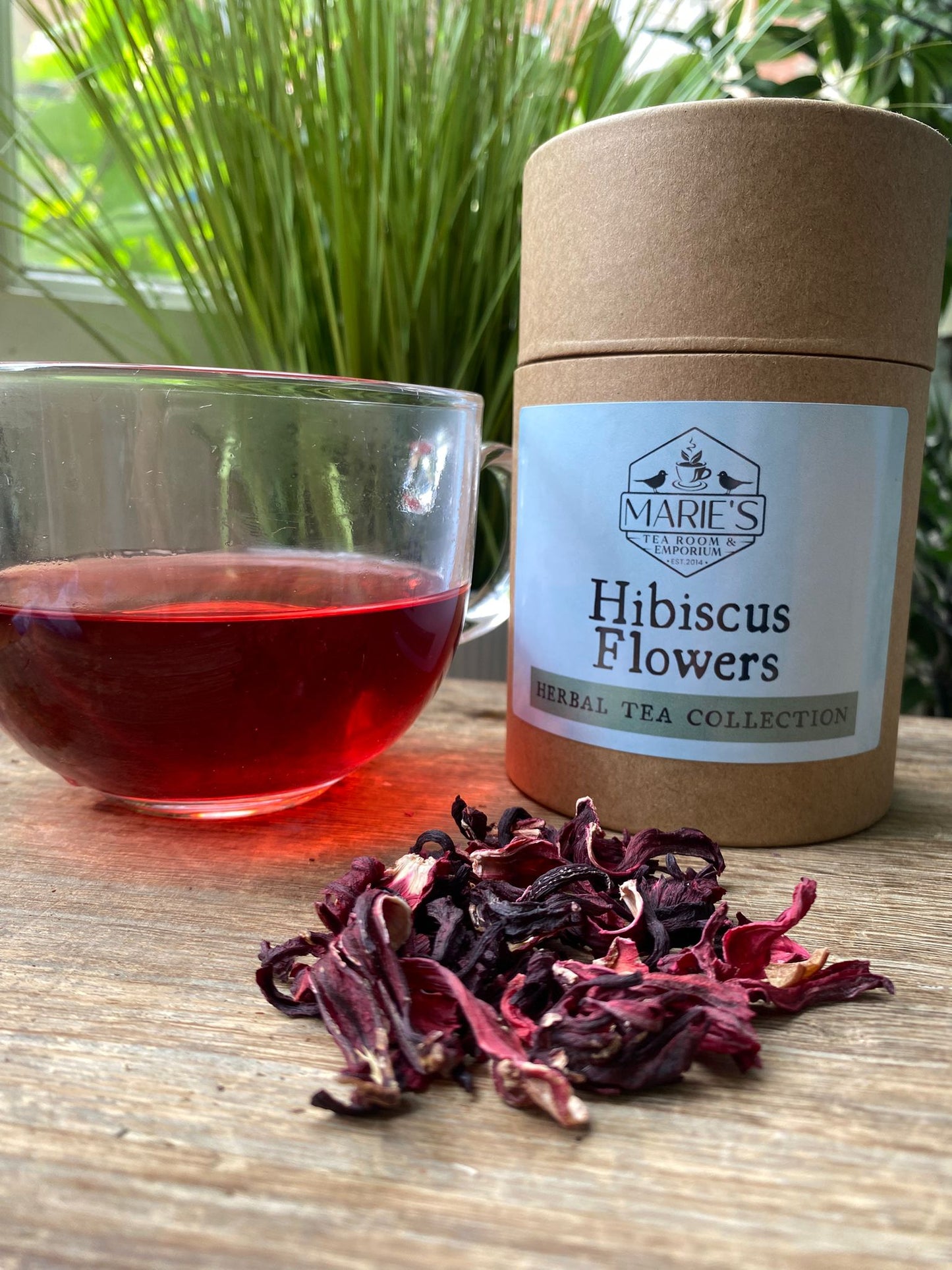 Hibiscus tea with a container labeled 'Marie's Herbal Tea Collection' on a wooden surface.