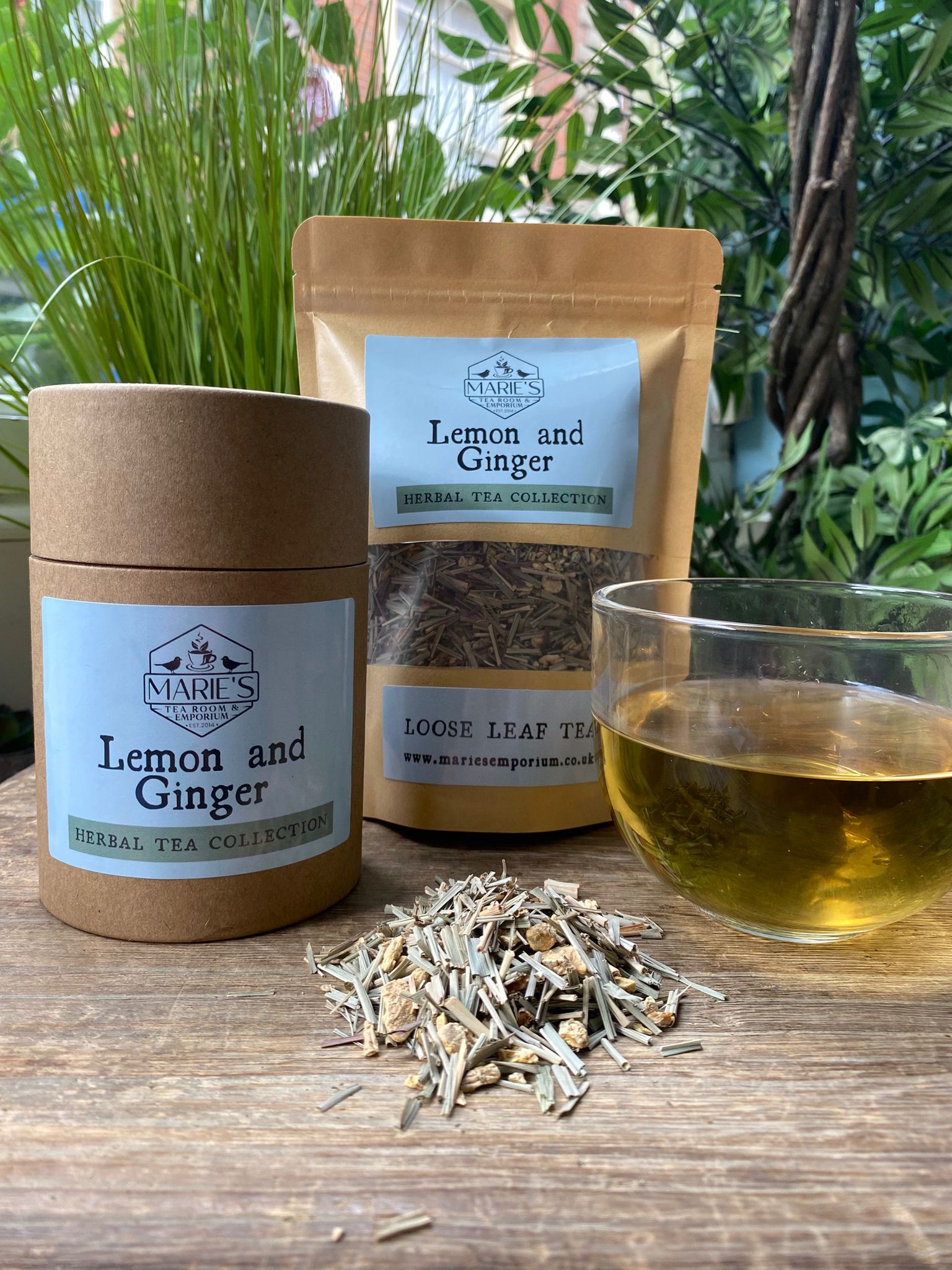 Marie's Lemon and Ginger tea set with a jar, packaging, and cup of tea on a wooden surface.
