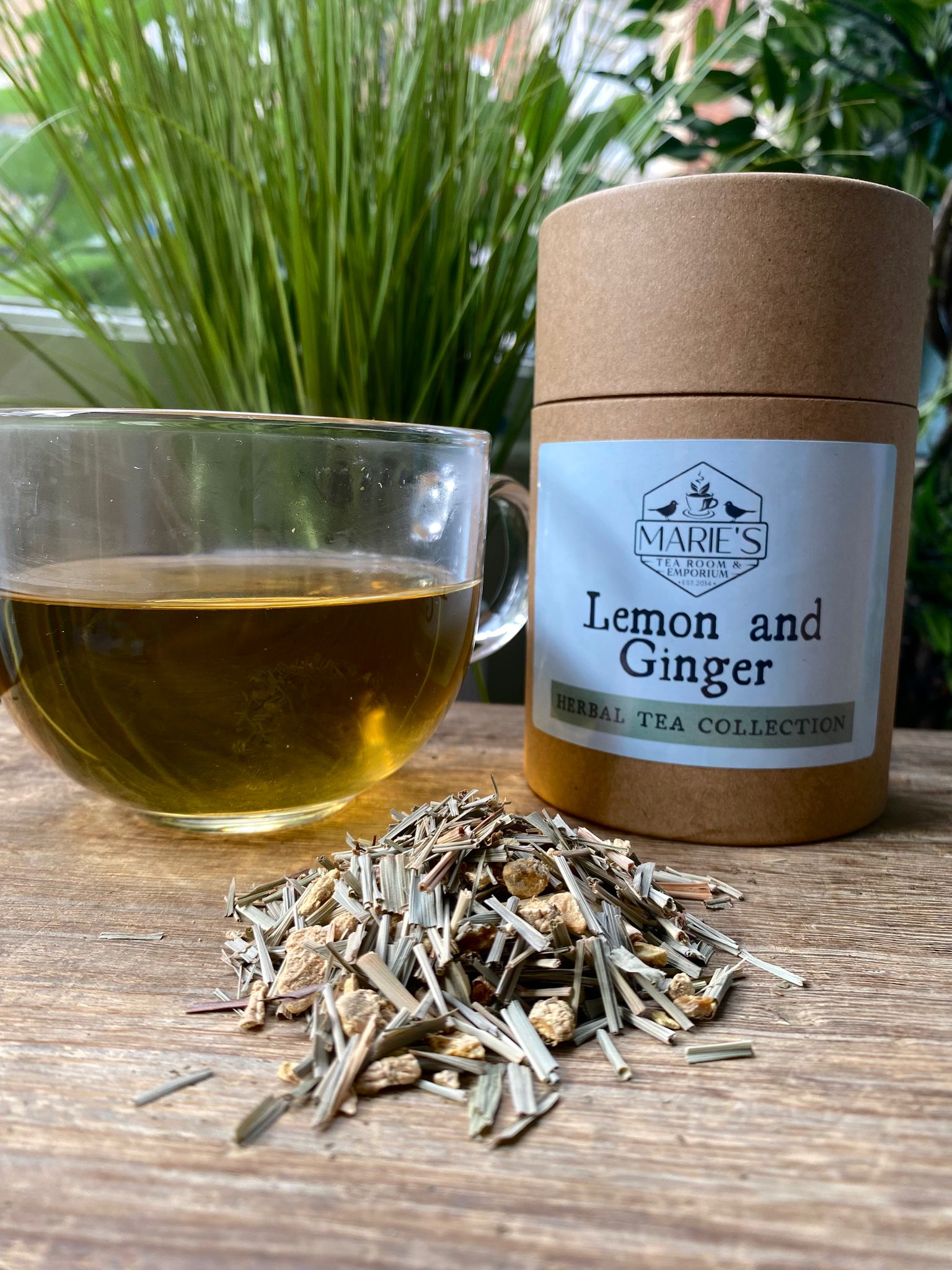 Marie's Lemon and Ginger tea packaging with a glass of tea and dried herbs on a wooden surface