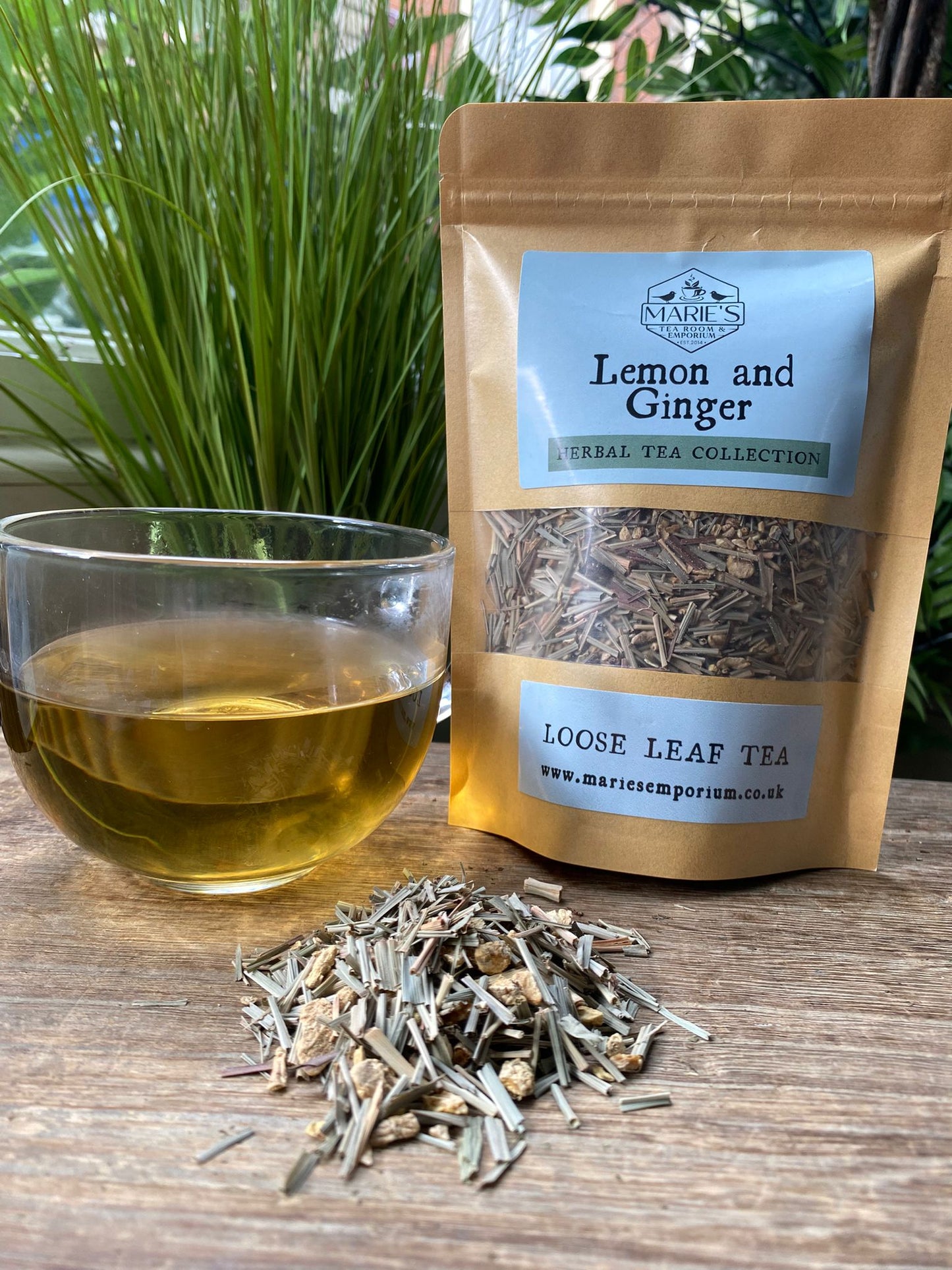 Loose leaf tea package labeled 'Lemon and Ginger' with a glass of tea and tea leaves on a wooden surface.