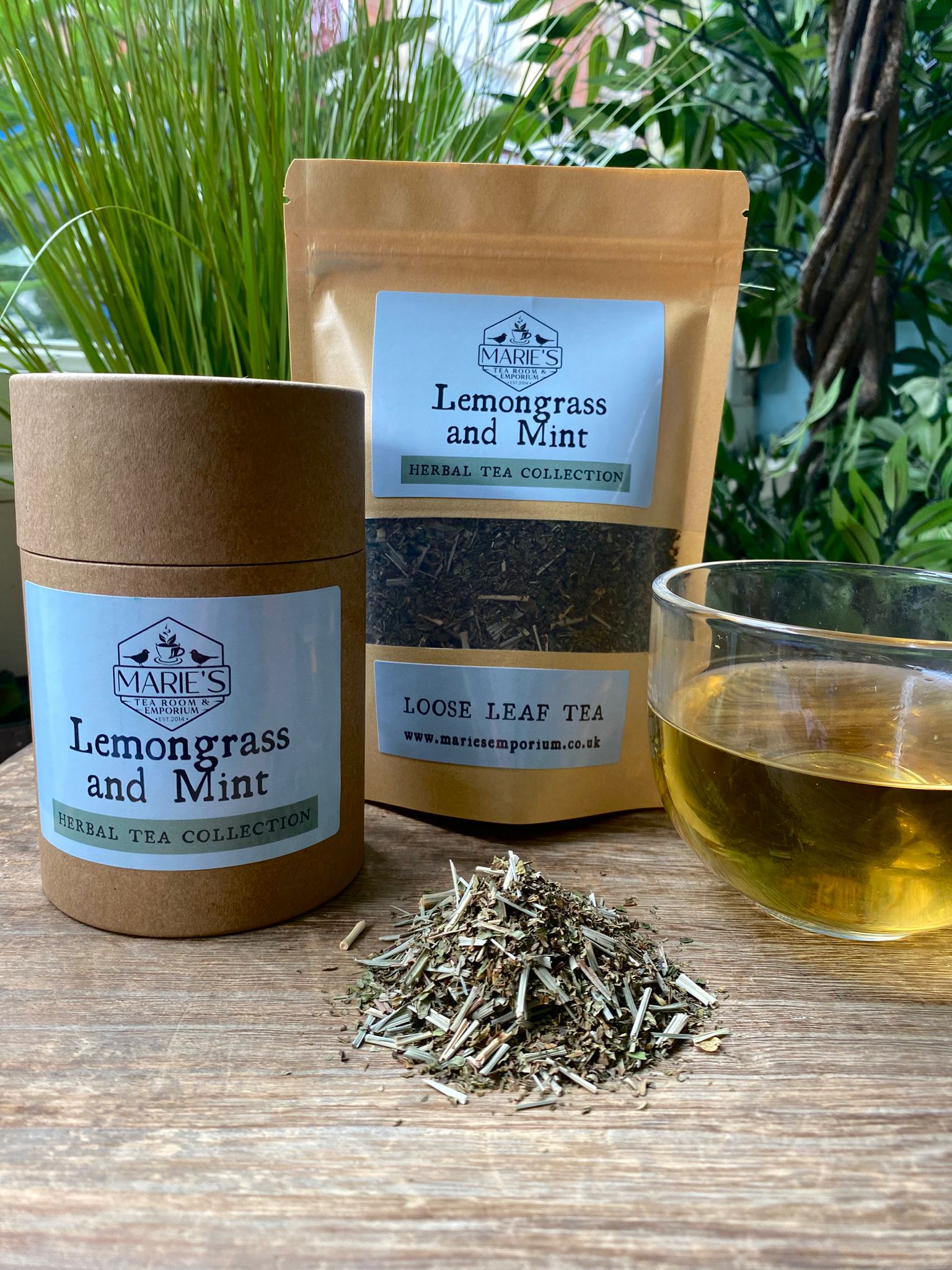 Marie's Lemongrass and Mint tea with packaging, loose leaves, and a cup of tea on a wooden surface.