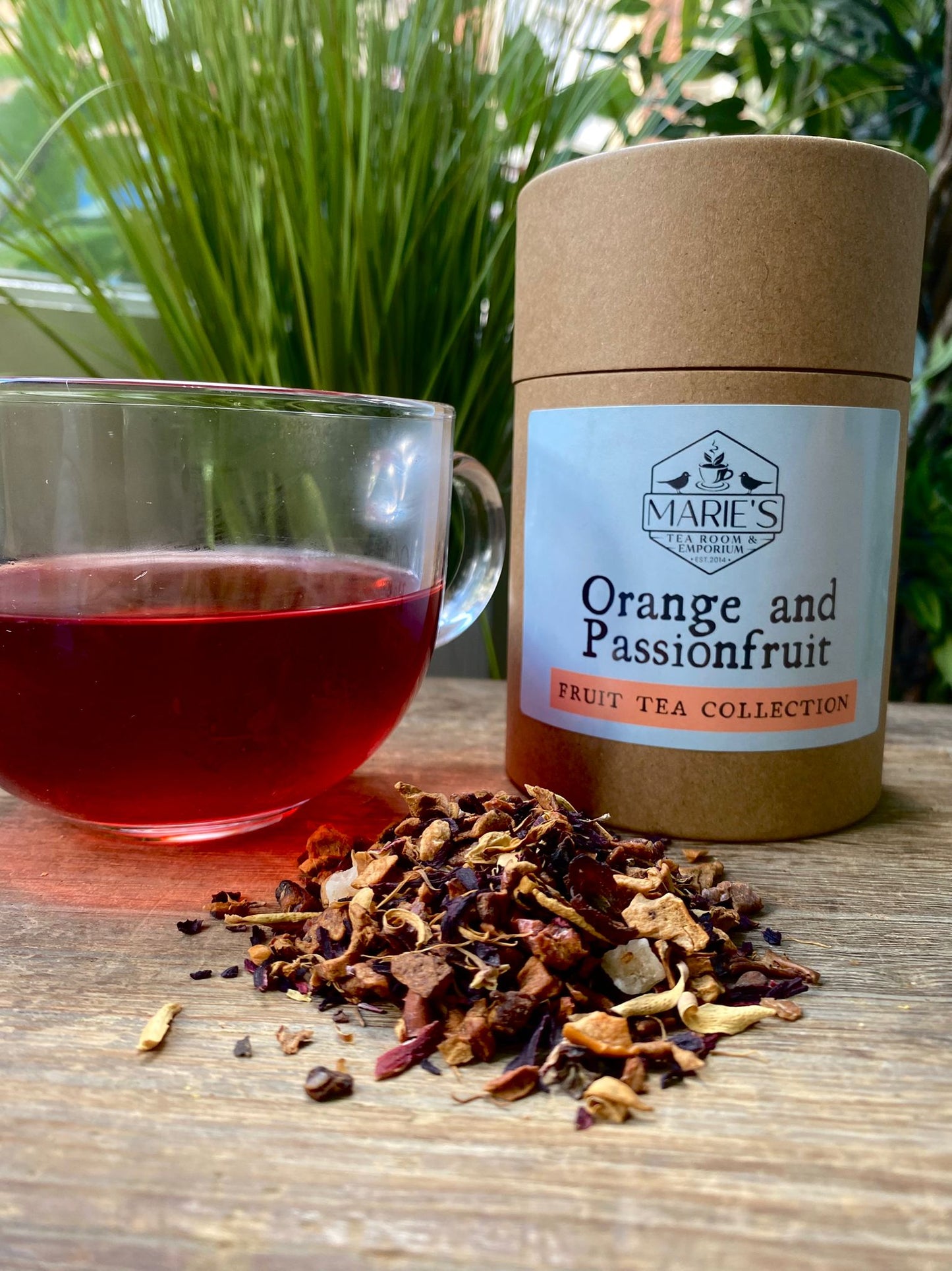maries Tea packaging with 'Orange and Passionfruit' flavor, a cup of tea, and loose tea leaves on a wooden surface.