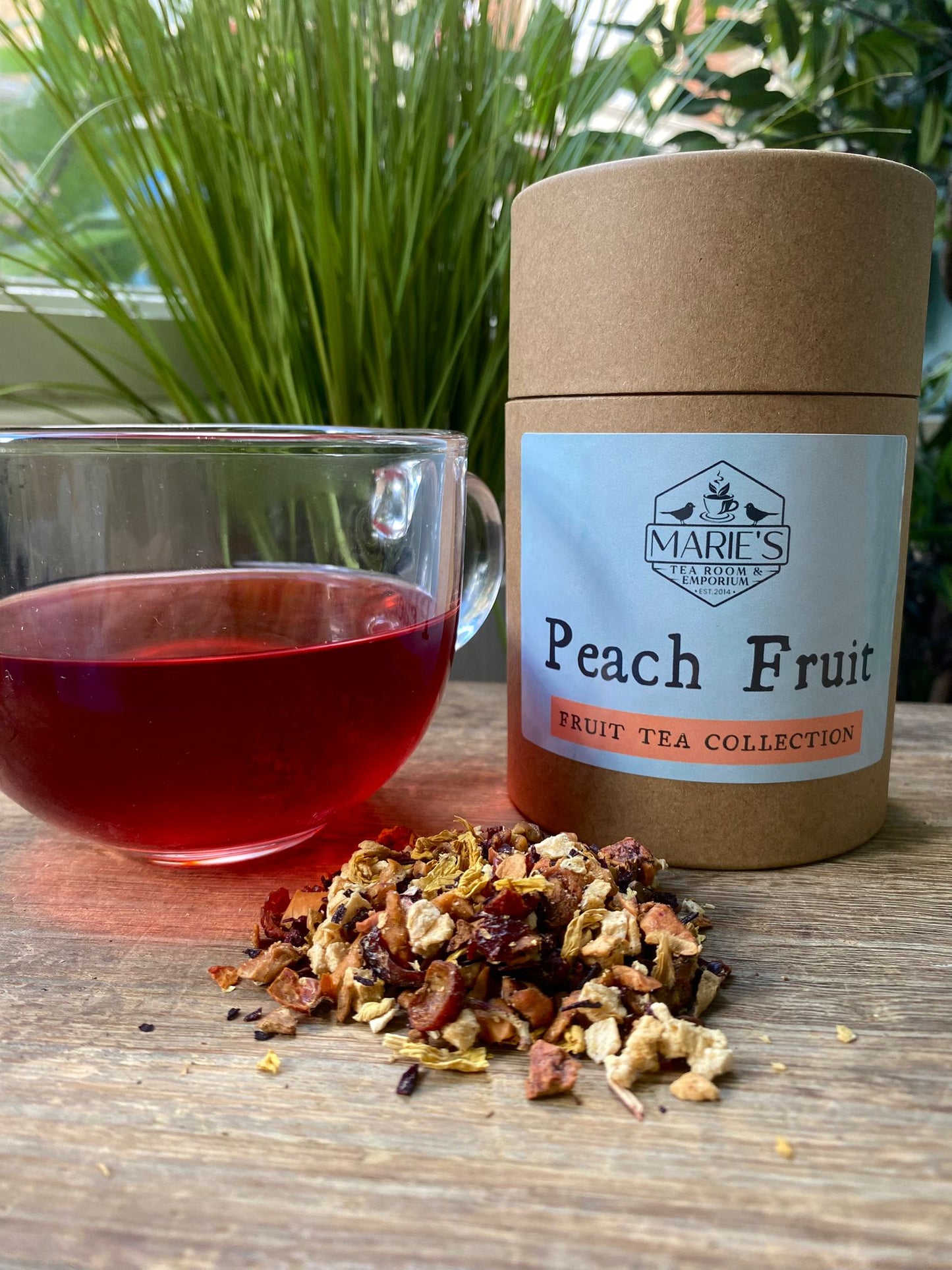 Marie's Tea packaging labeled 'Peach Fruit' with a glass of tea and tea leaves on a wooden surface.