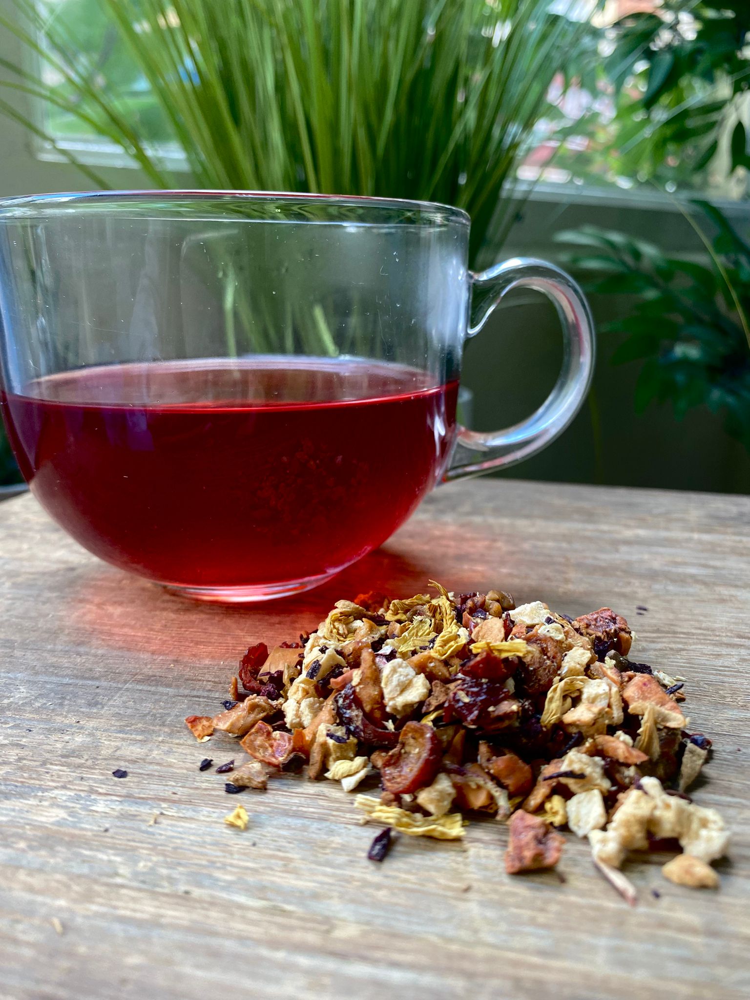 Marie’s Peach Fruit loose leaf tea with brewed fruit tea in a clear glass mug and loose tea leaves on a wooden surface