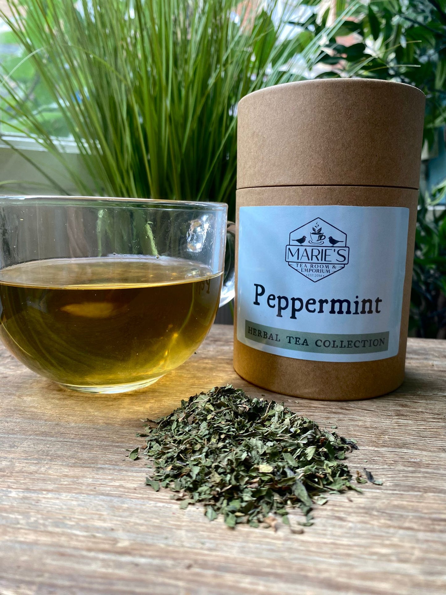 maries Peppermint tea with a glass of tea and dried peppermint leaves on a wooden surface.