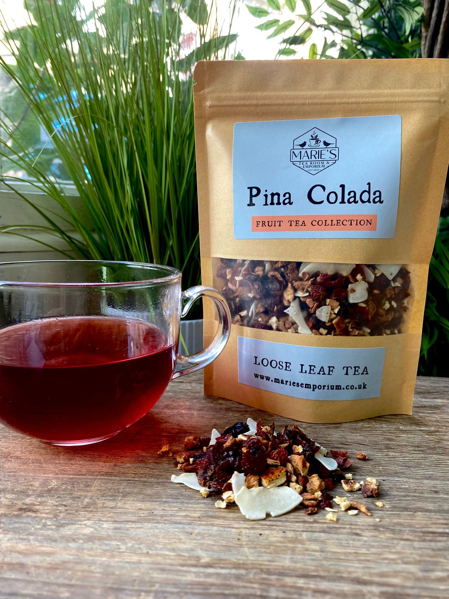 Pina Colada loose leaf tea package with a cup of tea on a wooden surface