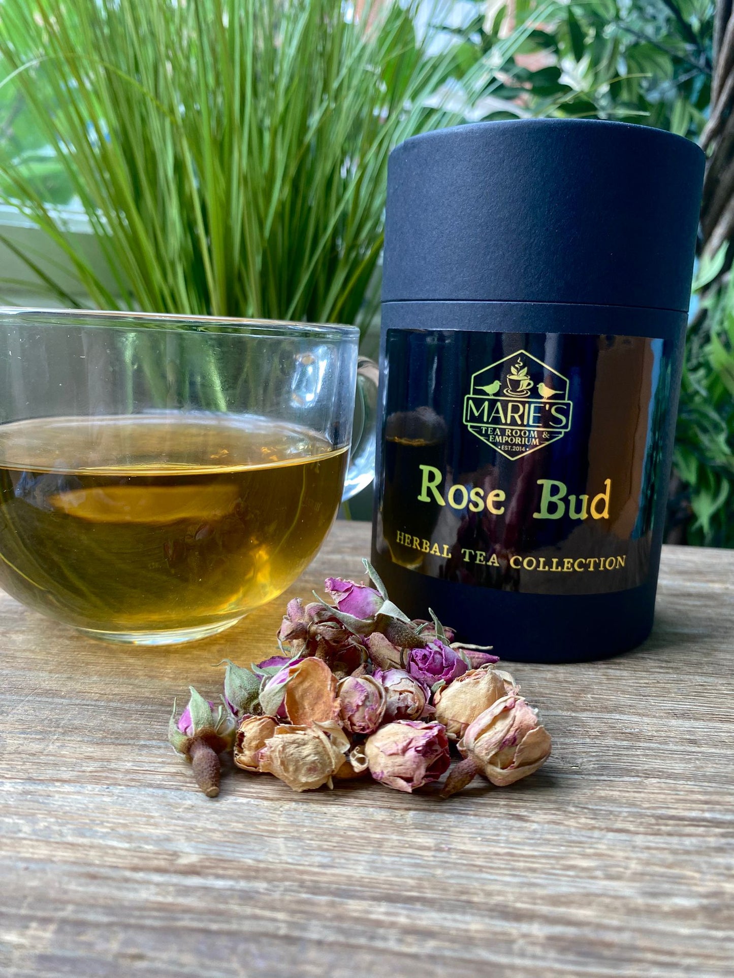 marie's Tea packaging labeled 'Rose Bud' with a glass of tea and dried tea leaves on a wooden surface.