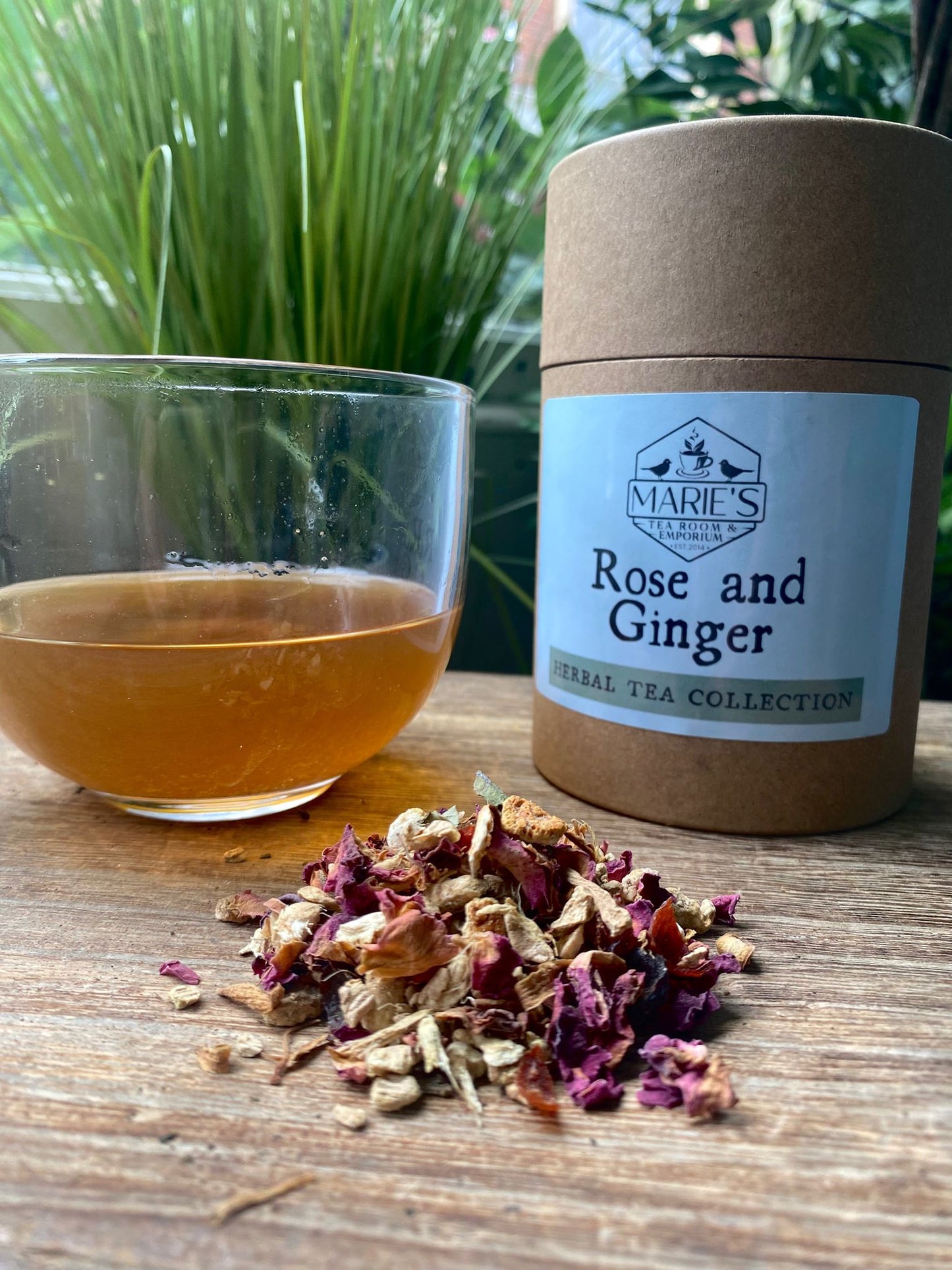 Marie's Teas Rose and Ginger tea with a glass of tea and tea leaves on a wooden surface.