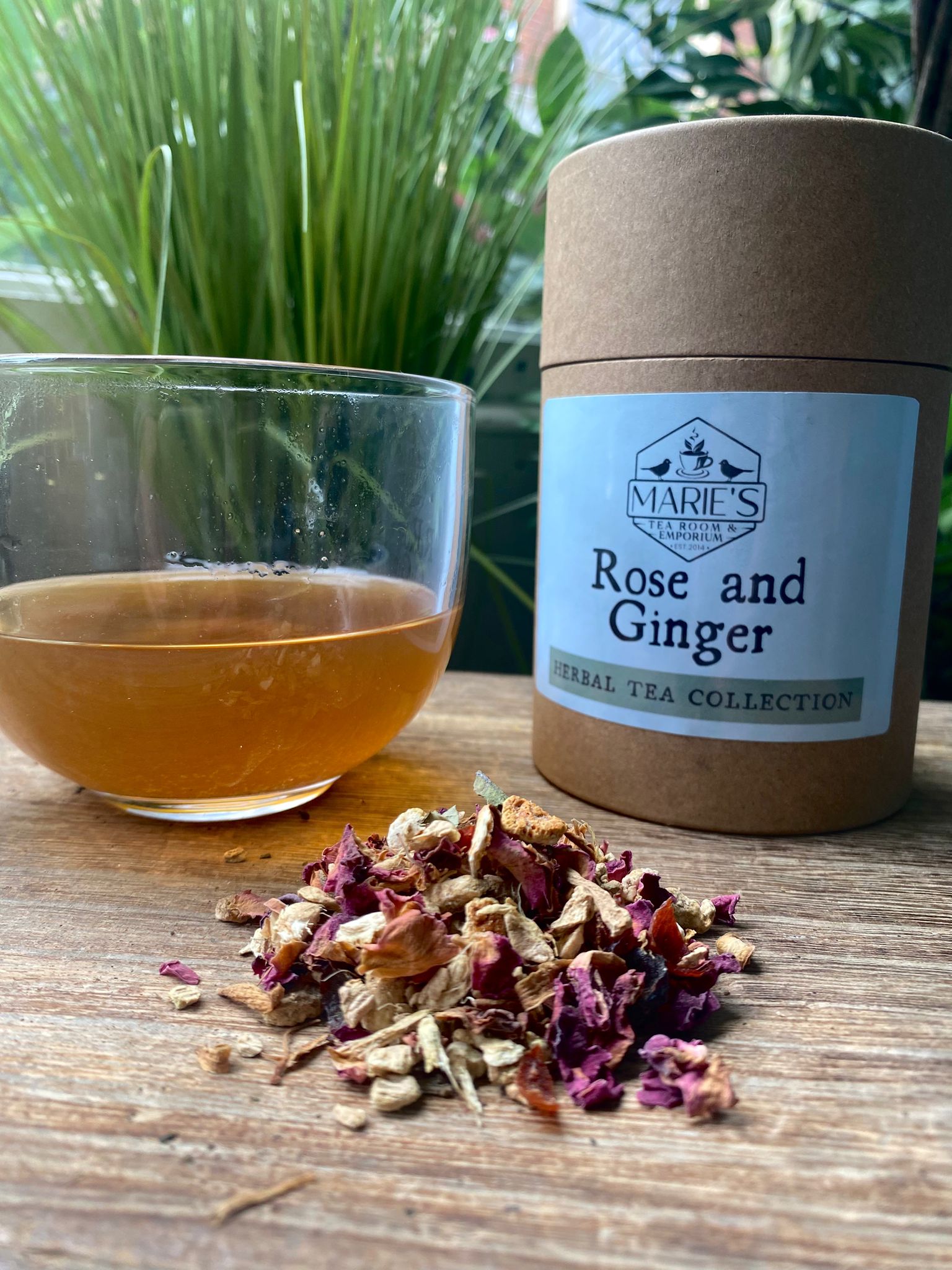 Marie's Teas Rose and Ginger tea with a glass of tea and tea leaves on a wooden surface.