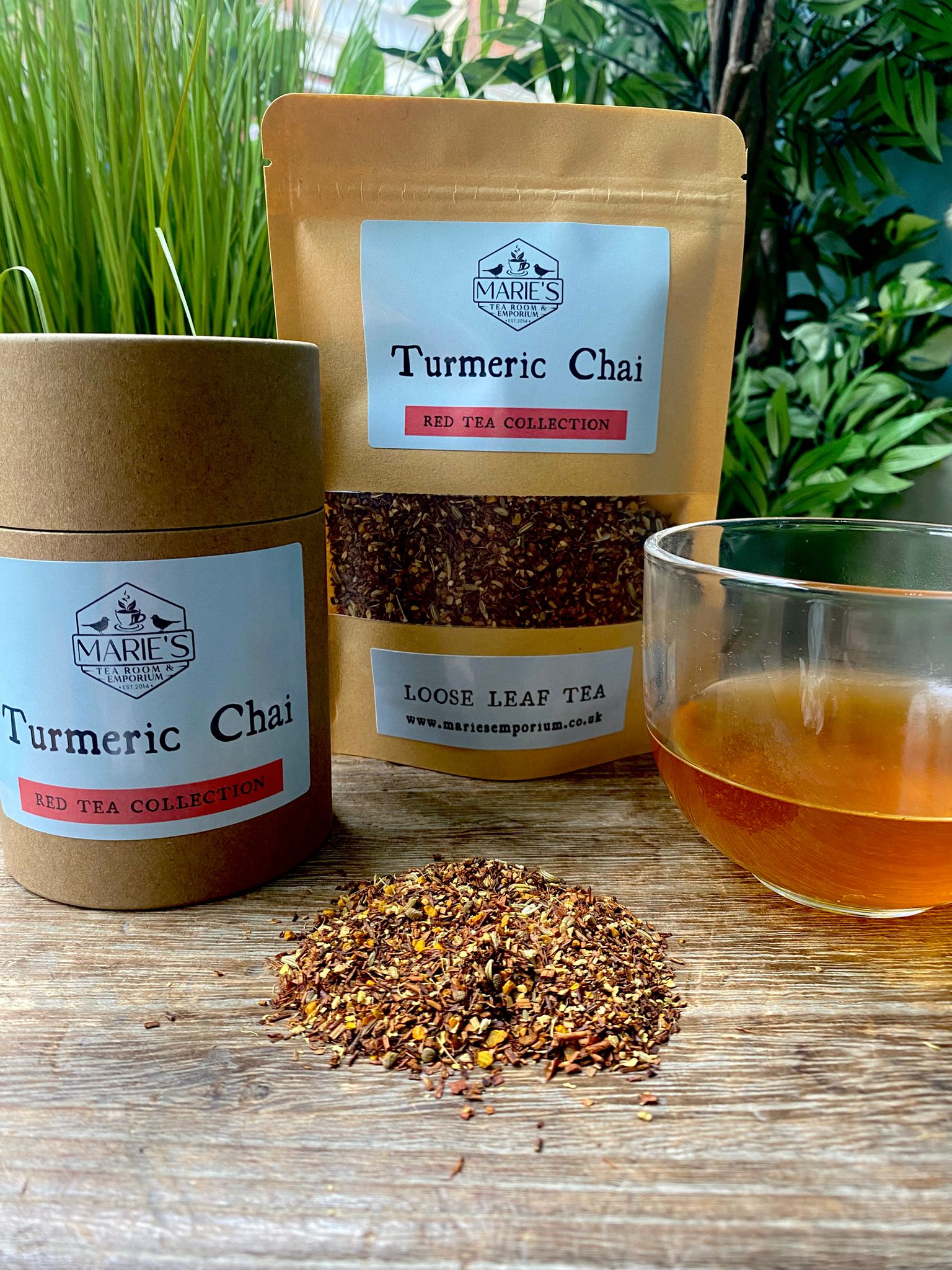 maries Turmeric Chai loose leaf tea packaging with loose leaves and a glass of tea on a wooden surface.