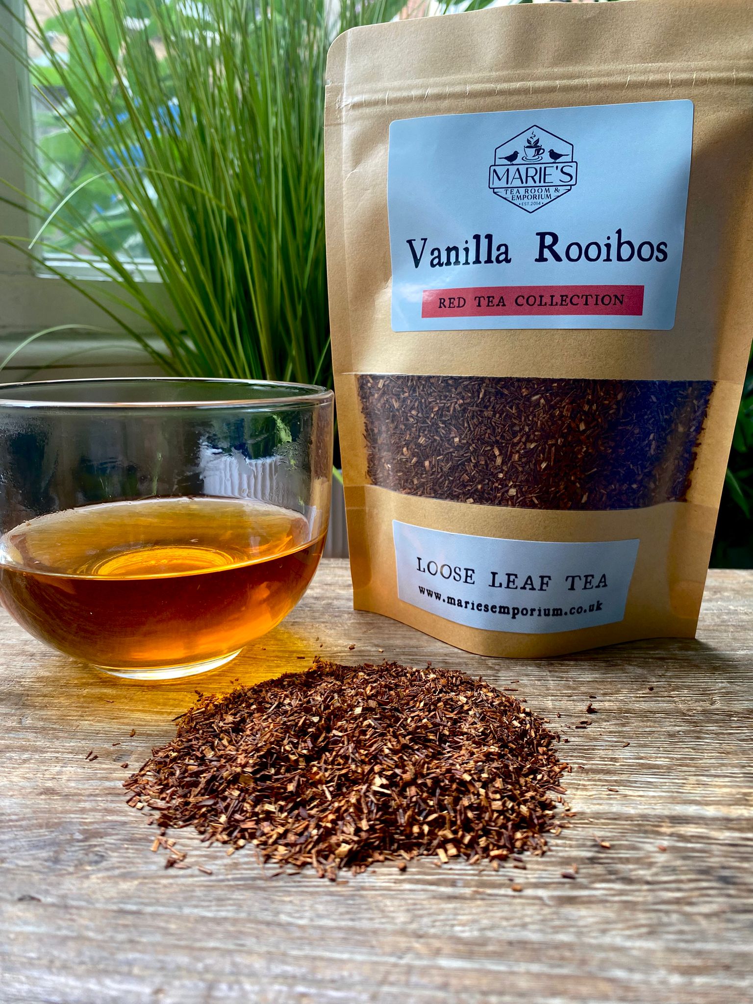 marie's Vanilla Rooibos tea package with a glass of tea and loose tea leaves on a wooden surface.