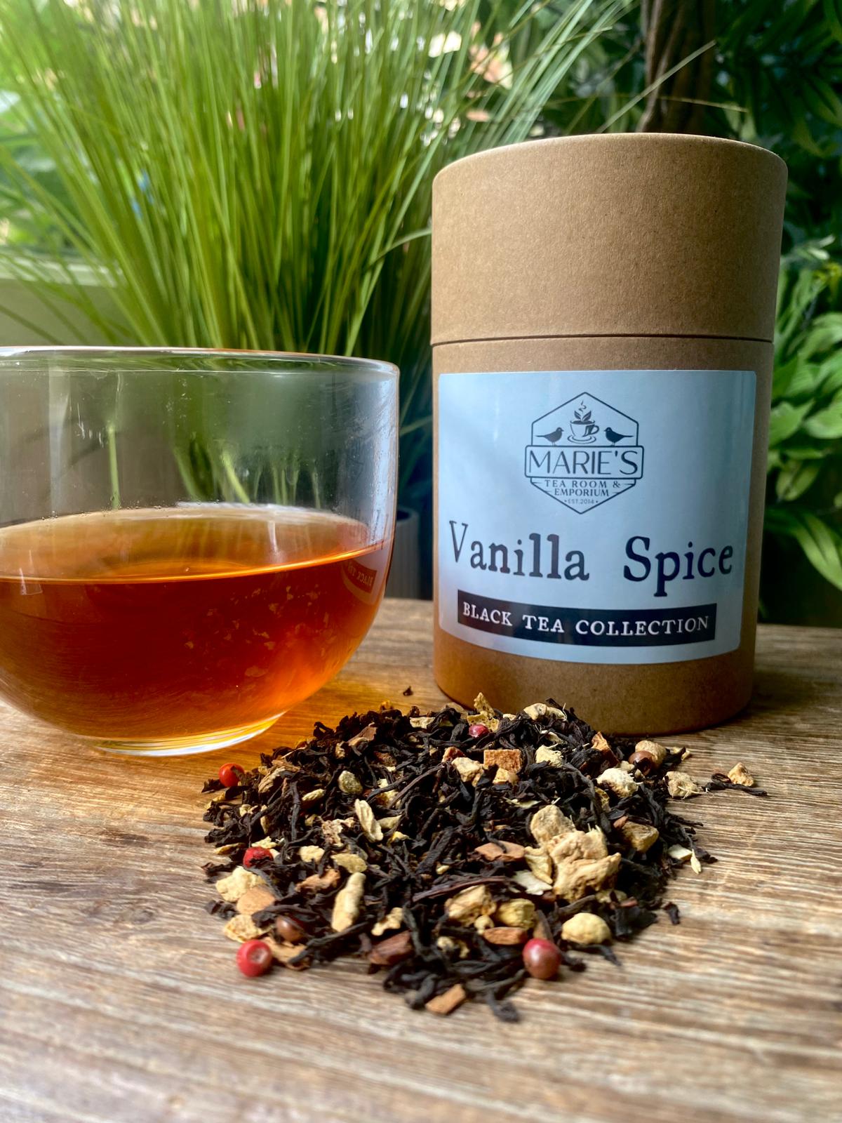 Vanilla Spice black tea maries collection with a glass of tea and tea leaves on a wooden surface.